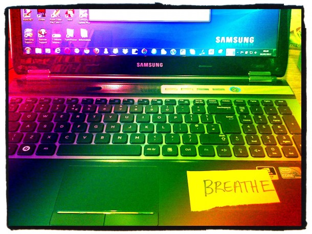 laptop computer with a note saying breathe on it