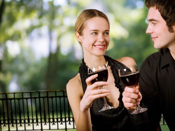 happy couple smiling at each other and holding glasses of red wine