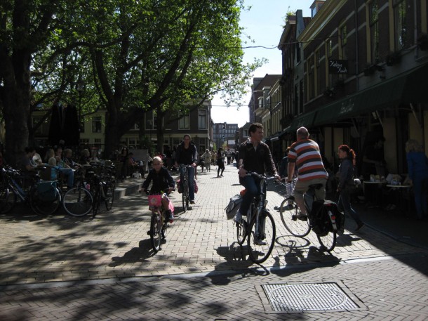 people riding bicycles through the streets of Delft