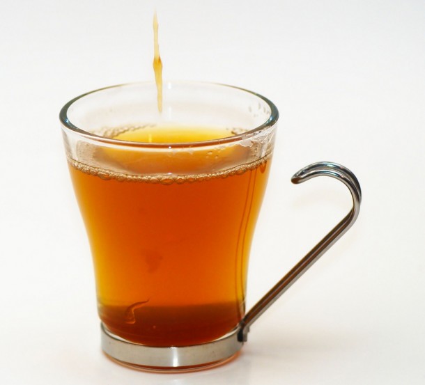A cup of black tea with honey dripping into it