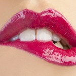 close-up of woman biting her pink lipsticked bottom lip