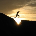 figure leaping across a ravine in the sunset