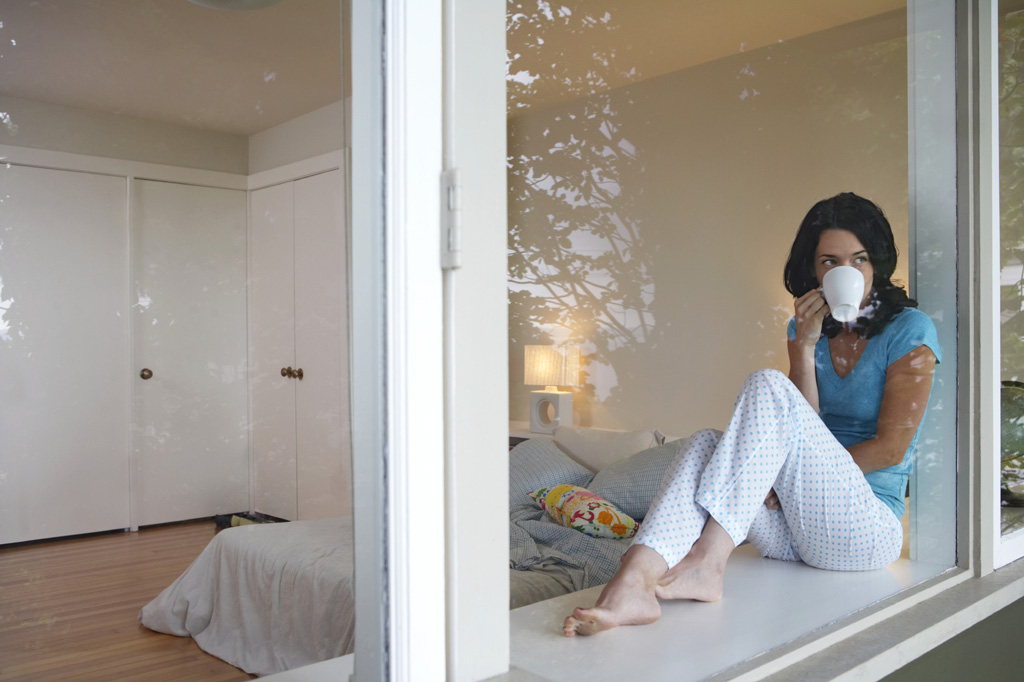 Woman sitting in windowsill drinking coffee to illustrate From Hormone Hell to Feeling Well