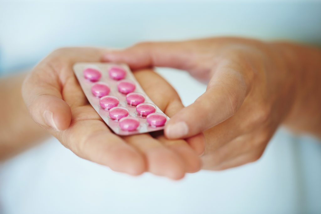 Blister pack of pink pills in hand to illustrate progresterone intolerance